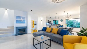 A modern living room with a gray sofa, yellow armchairs, and a fireplace.