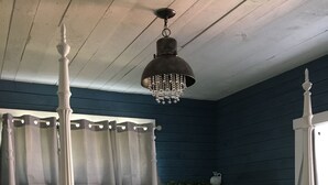 A four-poster bed with a floral bedspread, a wooden headboard, and a hanging chandelier. - Stonehaven Cottages - "The Birchview Suite Duplex - Lower Level" (Rice Lake)