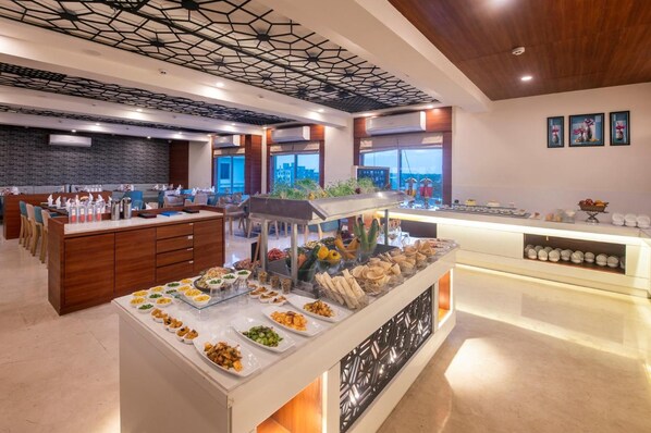 A buffet with various food items, a seating area with tables and chairs, and a modern ceiling design.