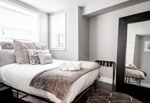 A modern bedroom with a bed, bedside table, and a window.