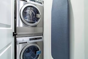 A stacked washer and dryer unit with a control panel and a blue handle.