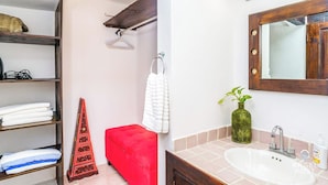 A bathroom with a sink, mirror, towel rack, and a red bench. - Lagoon Views with Beach Access, Pool and Patio (Cancún Q.R)