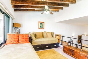 Ein modernes Wohnzimmer mit Sofa, Bett, Deckenventilator und einer Holzbank.