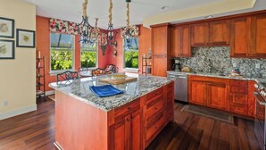 Una cocina con armarios de madera, encimera de granito y comedor con sillas y una mesa.