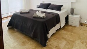 Un dormitorio moderno con una cama grande, cabecera blanca y una mesita de noche con lámpara.
