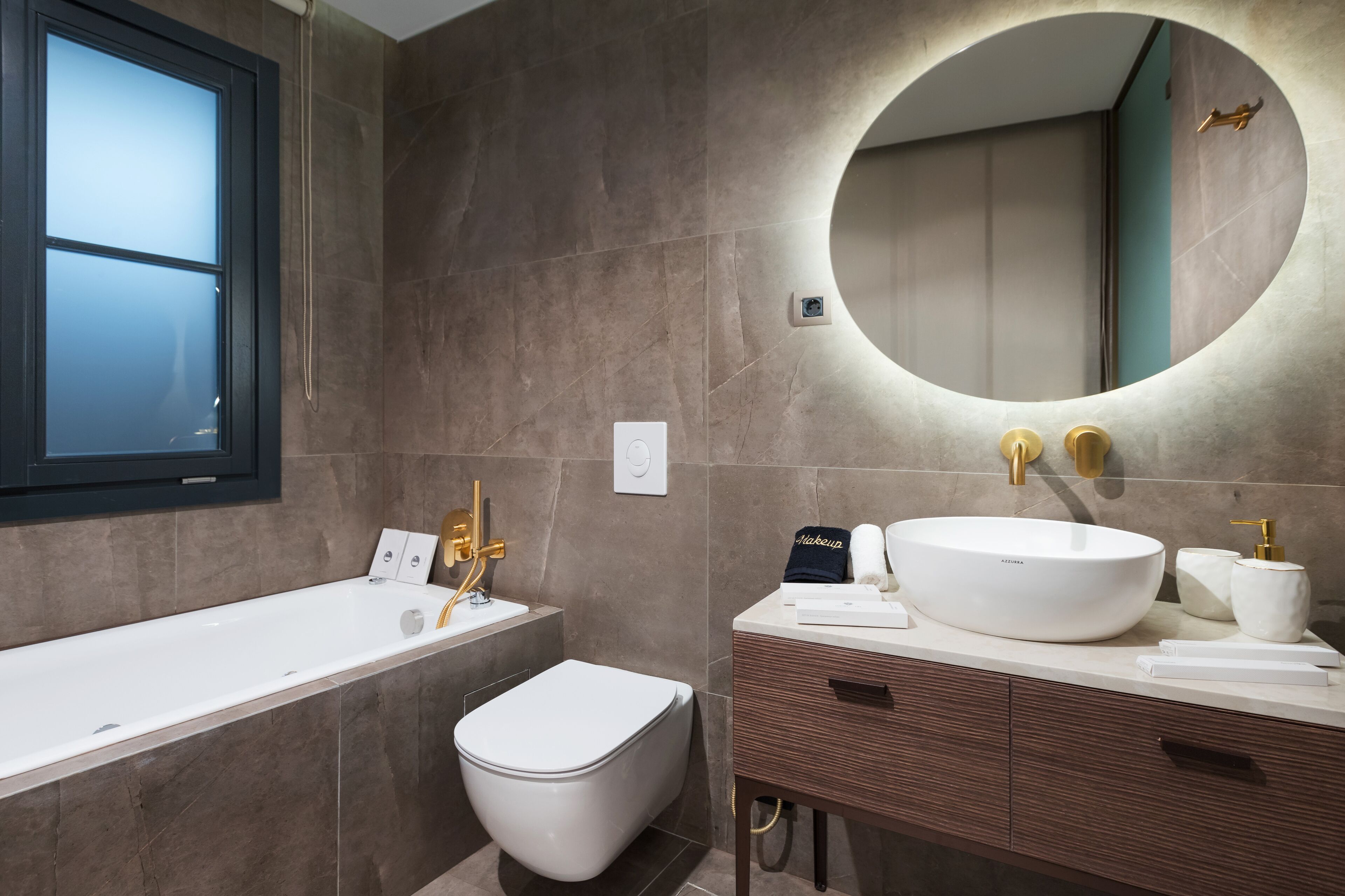 A modern bathroom with a bathtub, toilet, vanity with a sink, and a large mirror.