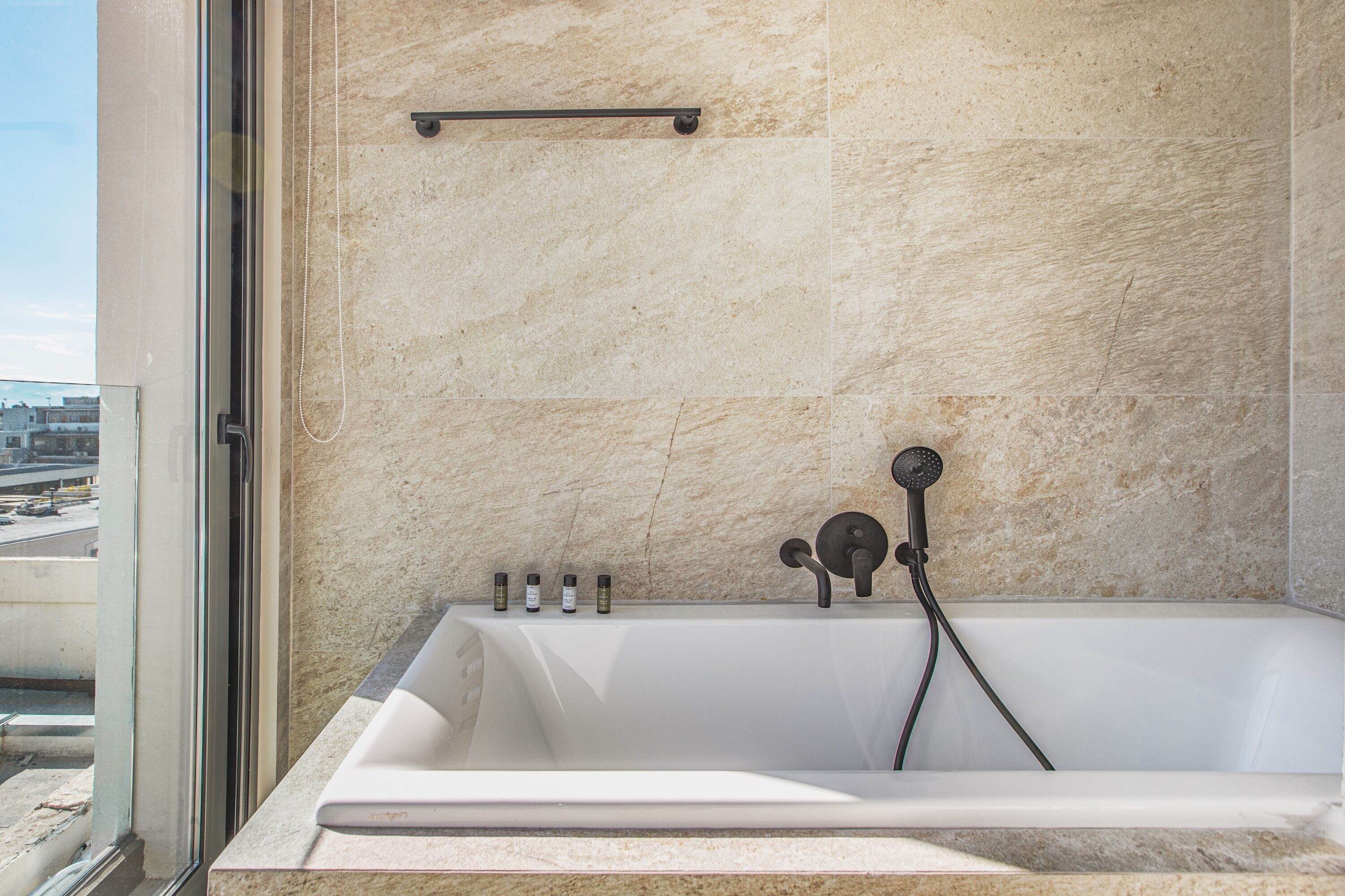 A modern bathroom with a bathtub, a showerhead, and a glass door.