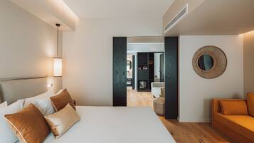 Quarto de hotel moderno com uma cama grande, um sofá e um espelho na parede.