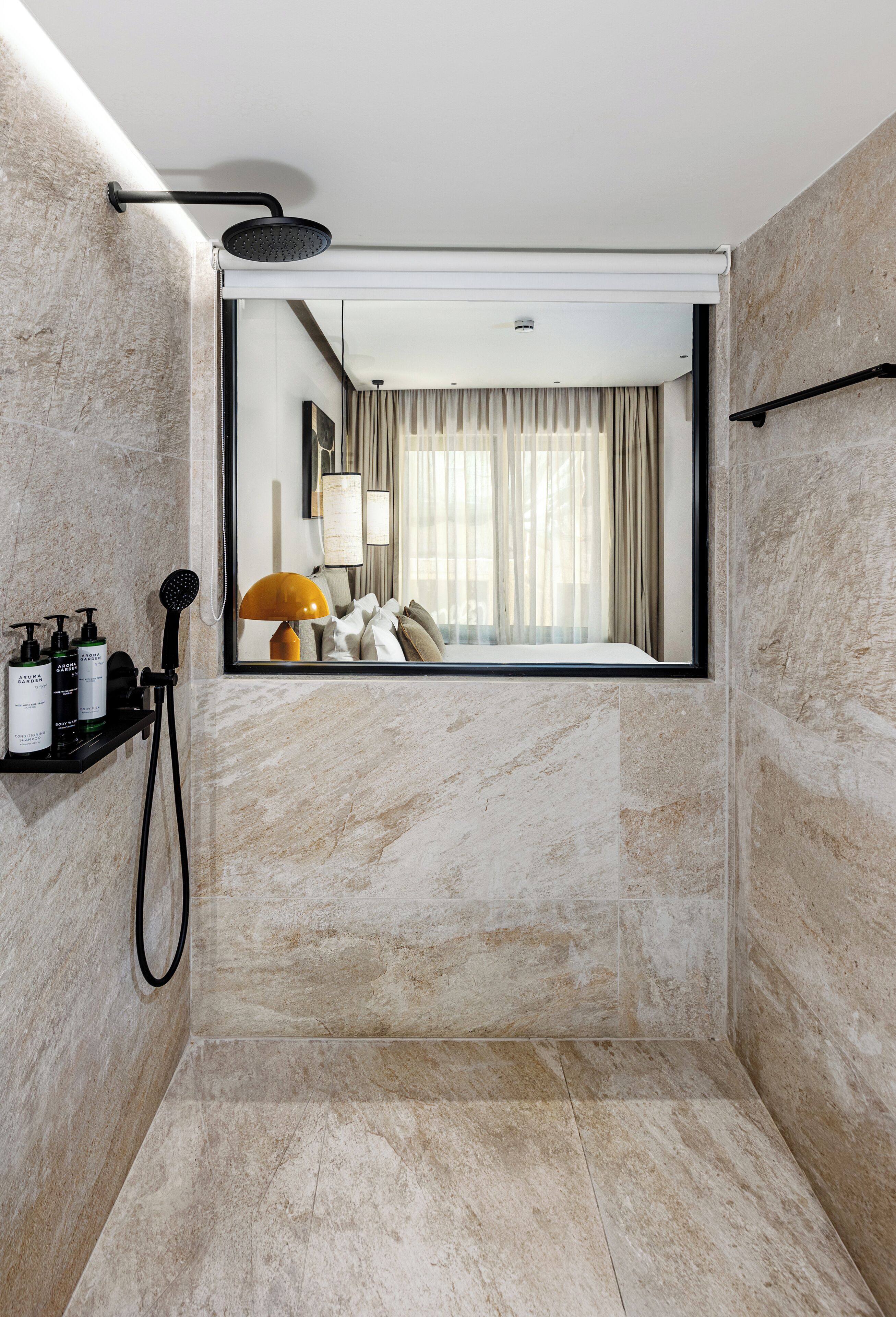 Une salle de bain moderne équipée d’une douche, d’un miroir et d’une étagère où sont rangés les produits de toilette.