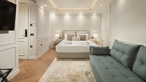 A modern bedroom with a large bed, bedside tables, a TV, and a sofa. - The Residence Aiolou Hotel & Spa (Athens)
