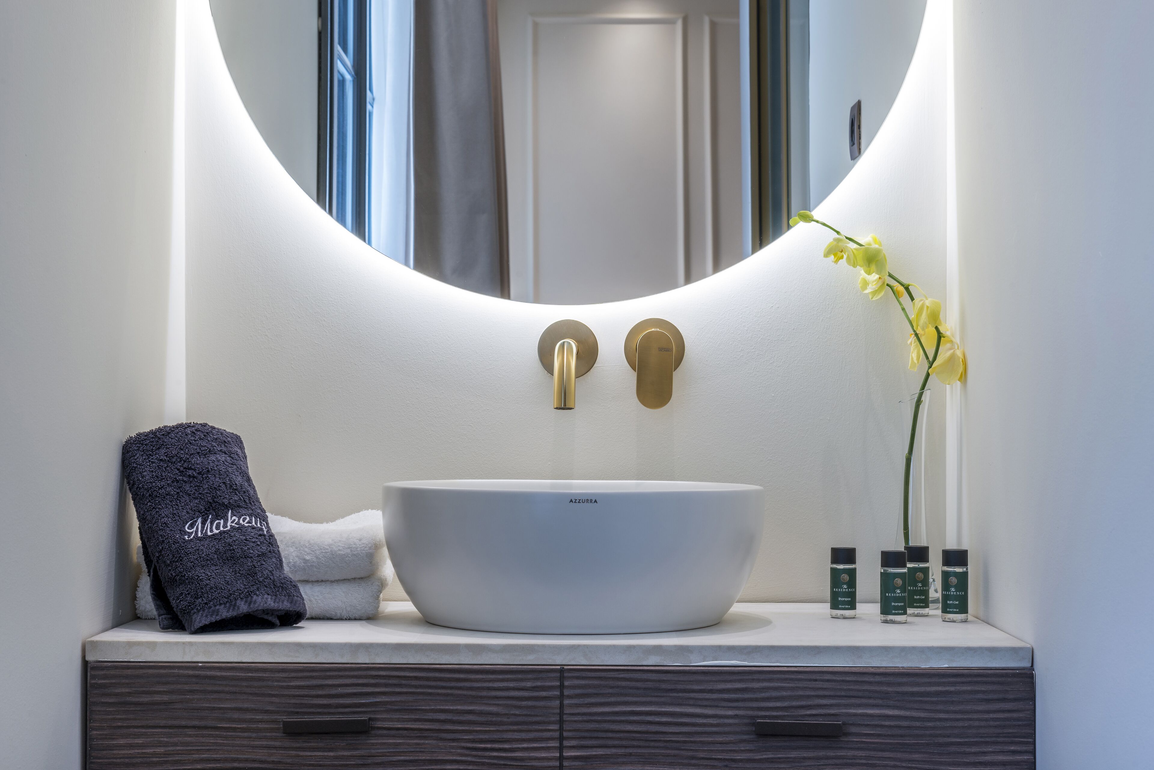 A bathroom with a white sink, a towel, and a mirror.