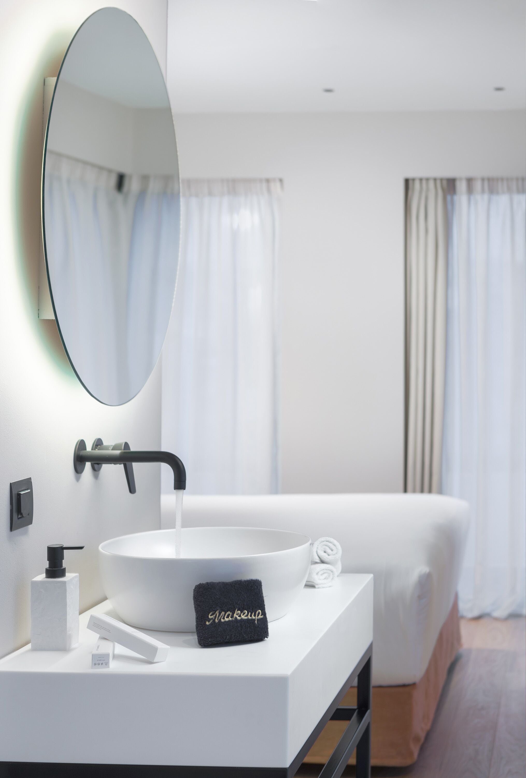 A modern bathroom with a white sink, a large mirror, a towel, and a bottle of soap.