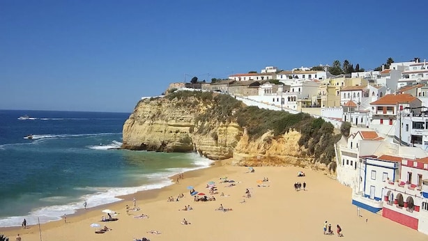 A coastal town with a beach, buildings on a cliff, and the sea.
