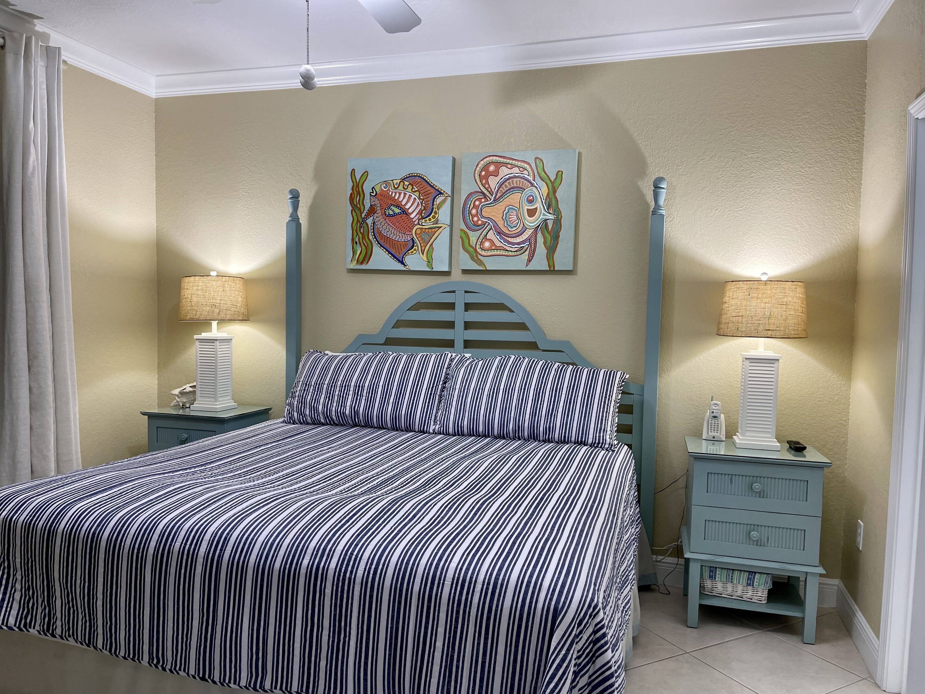 A bedroom with a bed, two nightstands, a lamp, a wall painting, and a small cabinet.