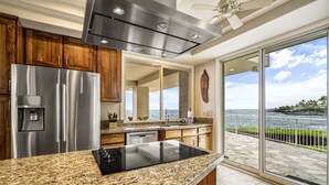 Una cocina moderna con un refrigerador de acero inoxidable, una estufa integrada y un amplio ventanal con vistas panorámicas.