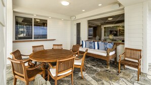 Un comedor con una mesa redonda de madera y sillas, suelo de piedra y vistas al exterior.