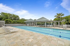 A swimming pool with lounge chairs and covered seating areas.