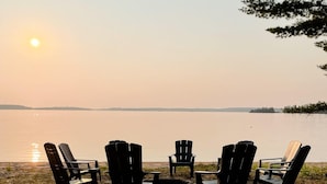 Un entorno junto al lago con sillas Adirondack dispuestas alrededor de un brasero.
