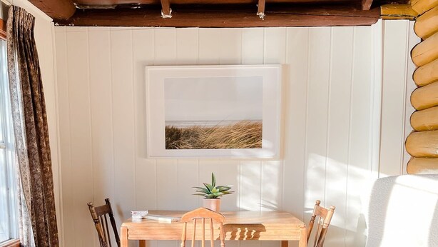 A cozy room with a wooden dining table, four chairs, a white sofa, and a patterned rug. - Bowerbird Beach Camp Cabin #2 (Sioux Narrows-Nestor Falls)