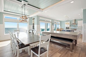 Uma cozinha espaçosa com uma ilha grande, armários brancos e vista para o oceano.