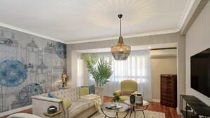 Ein Wohnzimmer mit Sofa, Sesseln, Couchtisch und einer großen Pflanze in einem Topf.