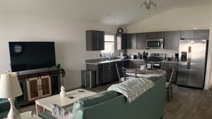 A modern kitchen with grey cabinets, a stainless steel refrigerator, and a microwave.