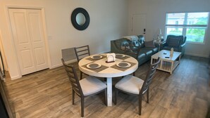A dining area with a round table, chairs, and a ceiling fan.