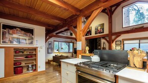 Una cocina con vigas de madera, una estufa y una zona de comedor con un sofá.