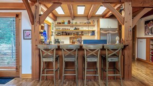 Una cocina con vigas de madera, una barra con taburetes y un refrigerador.