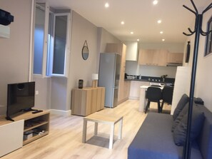 A compact living space with a kitchenette, a dining area, and a seating area with a sofa and a small table.