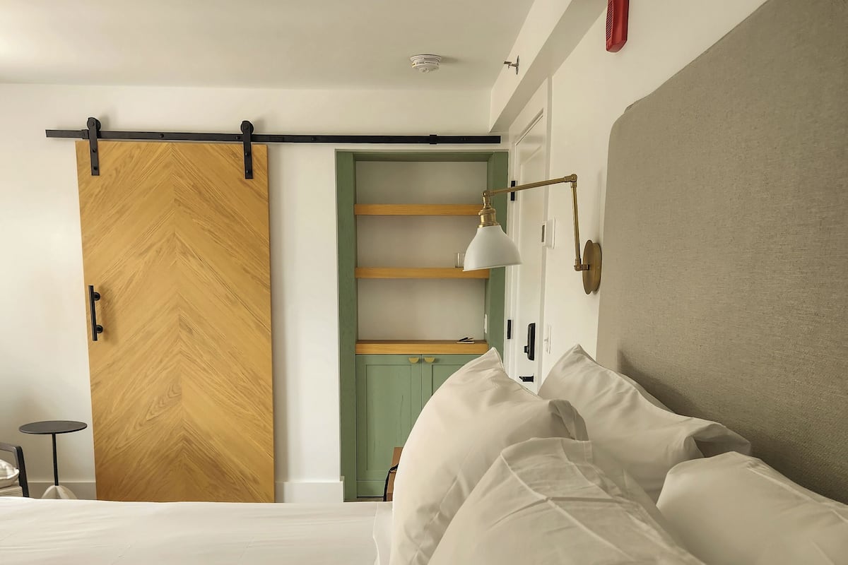 A bedroom with a bed, a sliding door, a bedside table, and a lamp.