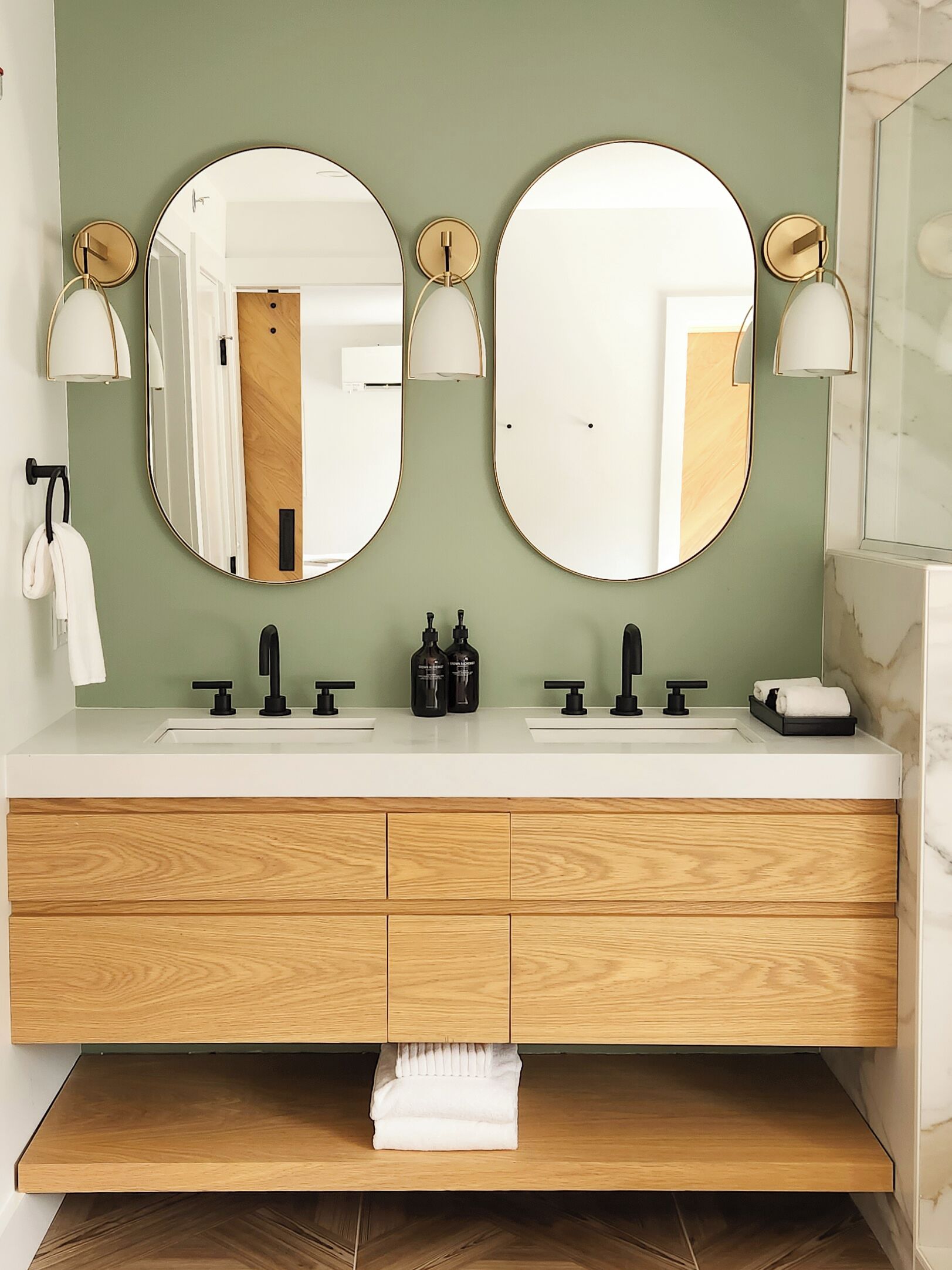 A bathroom with two sinks, three mirrors, and a wooden vanity with drawers.