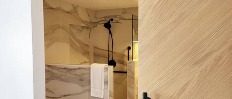 A modern bathroom with a marble wall, a wooden floor, and a sliding door.