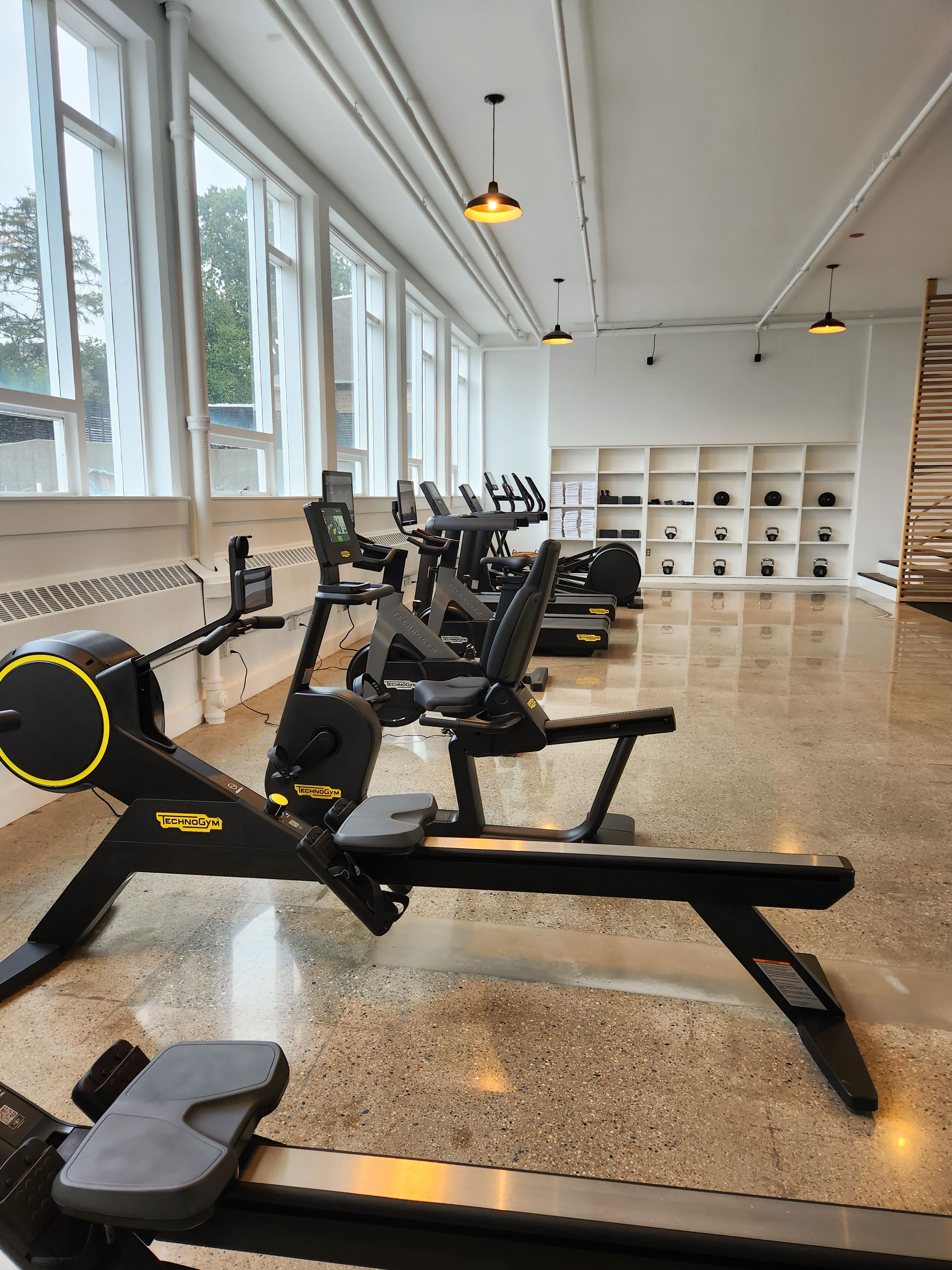 Un gimnasio con cintas de correr, bicicletas estáticas y una variedad de pesas.