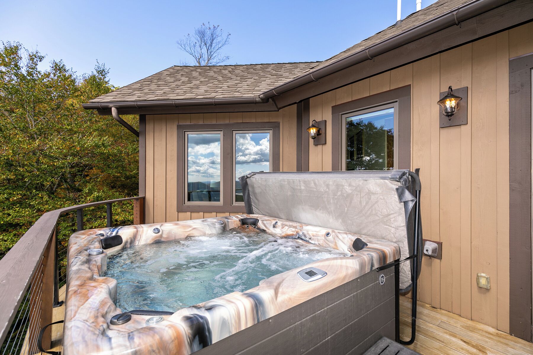 Een hottub met een houten terras, een raam en een lamp.