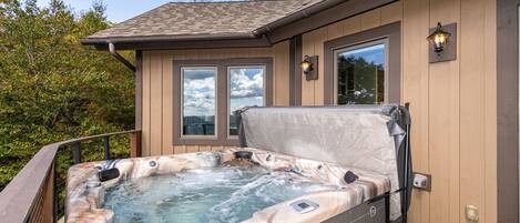 Een hottub met een houten terras, een raam en een lamp.