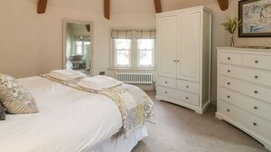 Un dormitorio con cama, cómoda, radiador, ventana y candelabro.