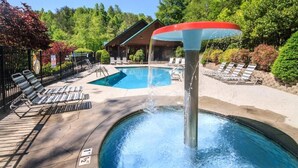 Un espace piscine avec des chaises longues, un jacuzzi et un bâtiment en arrière-plan.