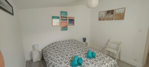 Un dormitorio con cama, mesita de noche, lámpara, silla y decoración en la pared.