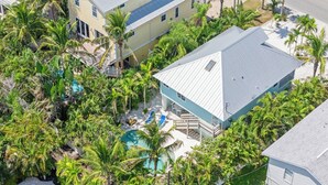Eine Vogelperspektive zeigt eine Wohngegend mit einem Haus, das einen Pool inmitten üppiger tropischer Vegetation hat.