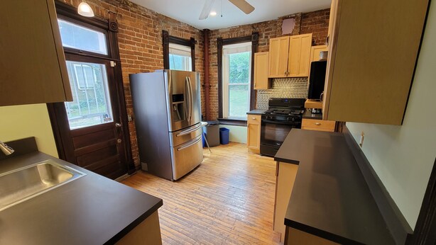 A compact kitchen with a refrigerator, stove, and wooden cabinets. - Historic 155 y/o 3-bedroom KC house with hot tub. (Kansas City)