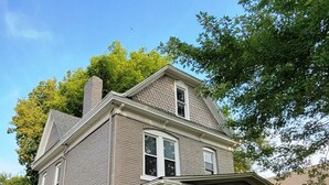 A two-story house with a front porch, brick exterior, and a chimney. - Historic 155 y/o 3-bedroom KC house with hot tub. (Kansas City)