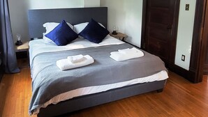 A neatly made bed with a grey and white duvet, two blue pillows, and a white towel on the side. - Historic 155 y/o 3-bedroom KC house with hot tub. (Kansas City)