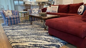 A living room with a red sofa, striped armchairs, a coffee table, and a patterned rug. - Downtown Coastal Craftsman Escape close to Riverwalk, Amphitheater, Beaches!! (Wilmington)