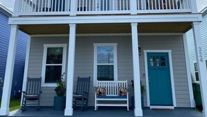 A two-story house with a balcony, a front door, and a porch with two chairs and a bench. - Downtown Coastal Craftsman Escape close to Riverwalk, Amphitheater, Beaches!! (Wilmington)