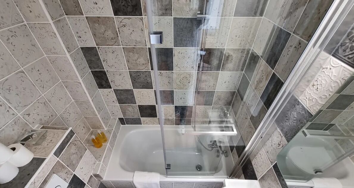 A bathroom with a glass-enclosed shower, a bathtub, and a toilet.