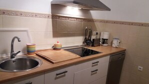 A compact kitchen with a sink, stove, and a coffee maker.