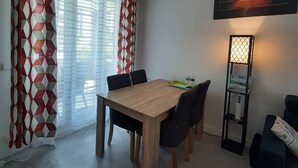 Een eethoek met een houten tafel en stoelen, een staande lamp en decoratieve gordijnen.