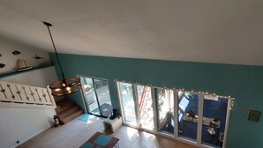 Ein geräumiger Raum mit einem großen Fenster, einer Treppe und einem Deckenventilator.