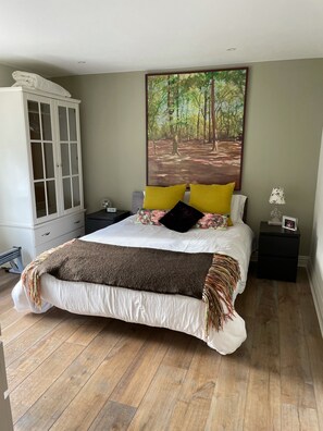 A bedroom with a bed, a wardrobe, a nightstand, and a painting on the wall. - Grand open plan modern home with heaps of light, and close to London (Kingston upon Thames)